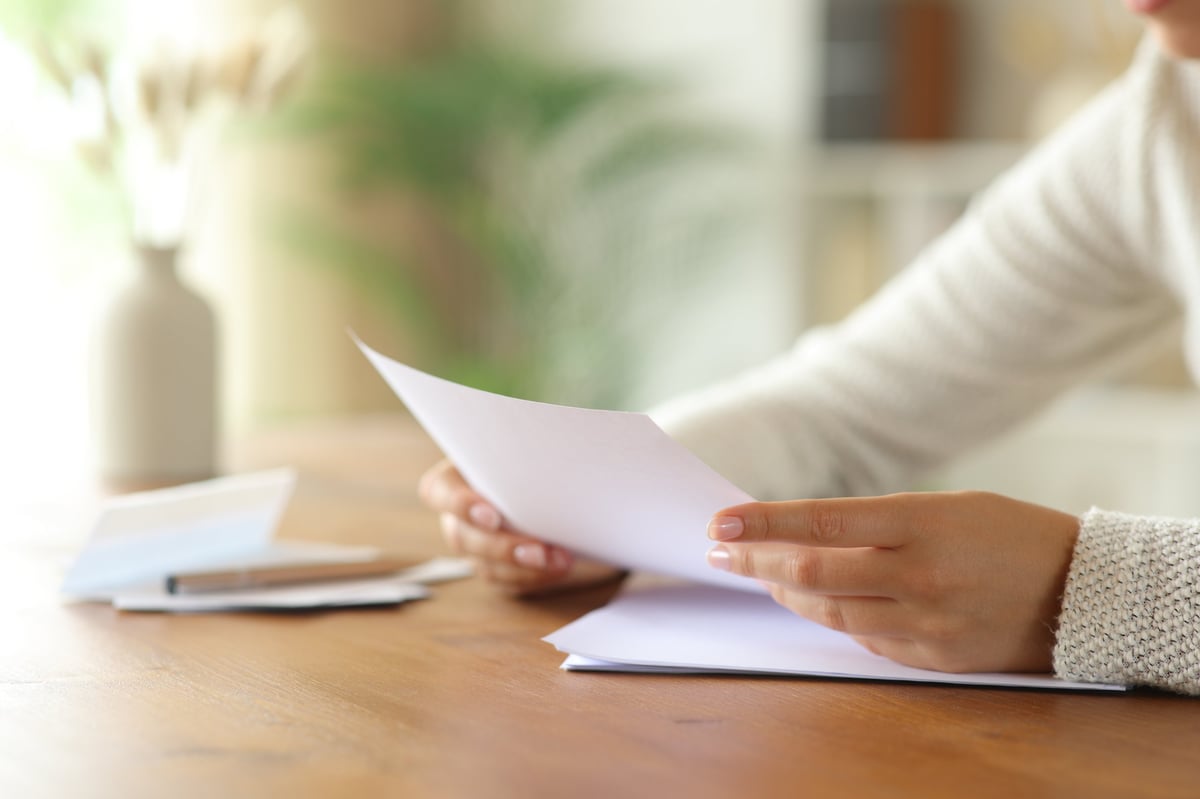 Close up of hands reading and writing, studying at a wooden table